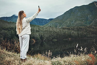Buy stock photo Woman, selfie and forest, mountains or nature in search of network, connection or internet outdoor. Young person camping, travel or hiking with adventure photography or mobile for location by lake 