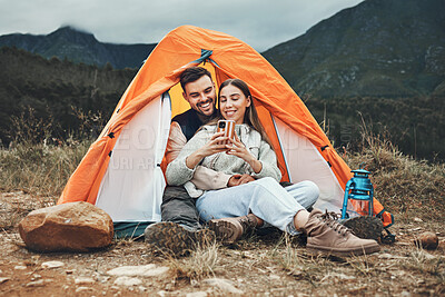 Buy stock photo Camping, couple and relax with phone in tent for reading, social media or communication in nature. Happy, people and together in mountain, forest or woods with cellphone, meme or online connection
