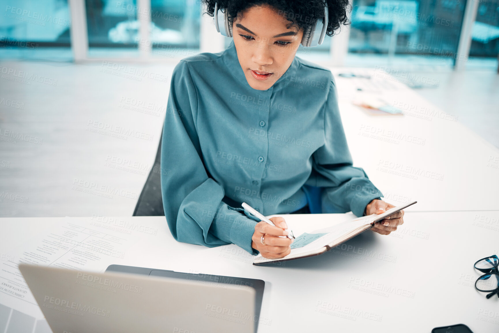 Buy stock photo Headphones, technology and woman writing notes in the office doing research for creative project. Notebook, laptop and professional female designer working, planning and listen to music in workplace.