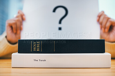 Books, stack and closeup on desk for faith, Abrahamic religion and question mark on poster for study in home. Person, holy spirit and education for choice with Jesus, Moses and worship God with sign