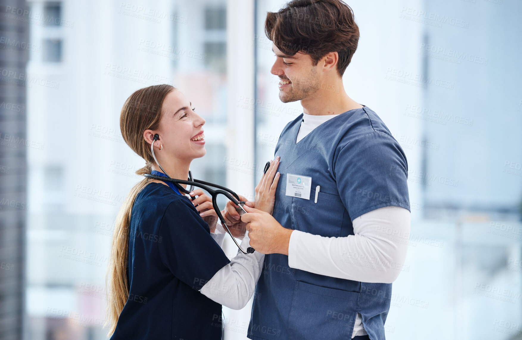 Buy stock photo Couple, hospital and doctors with stethoscope for love, relationship and work romance in clinic. Healthcare team, happy and playful man and woman for medical service, support and medicare career