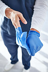 Closeup, doctor and man with gloves, healthcare and safety with protection, wellness and uniform. Zoom, person and medical professional with hands, surgery and policy in a hospital, scrubs and nurse