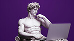 Sculpture or statue of David working on a modern laptop on a purple background