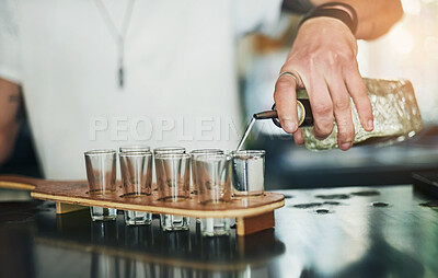 Buy stock photo Cropped shot of an unidentifiable bartender pouring shots behind the bar