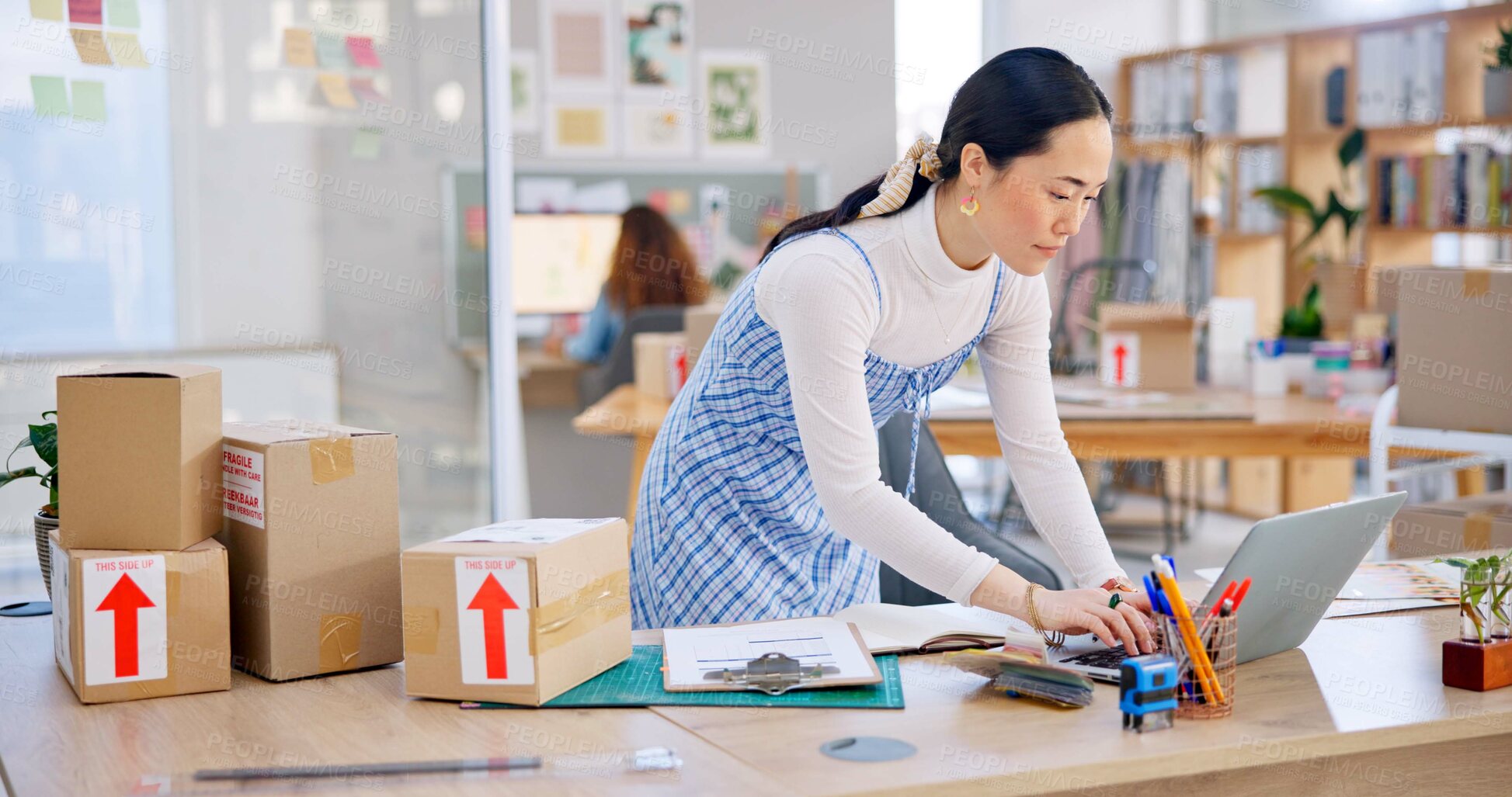 Buy stock photo Ecommerce, Asian woman with checklist and boxes at laptop, reading sales or inventory at fashion startup. Online shopping, delivery and small business owner, stock list for web shop package checking.