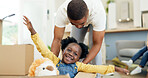 Father, child and playing in a box while moving house with a black family together in a living room. Man and a girl kid excited about fun game in their new home with a smile, happiness and adventure