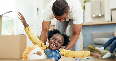 Father, child and playing in a box while moving house with a black family together in a living room. Man and a girl kid excited about fun game in their new home with a smile, happiness and adventure