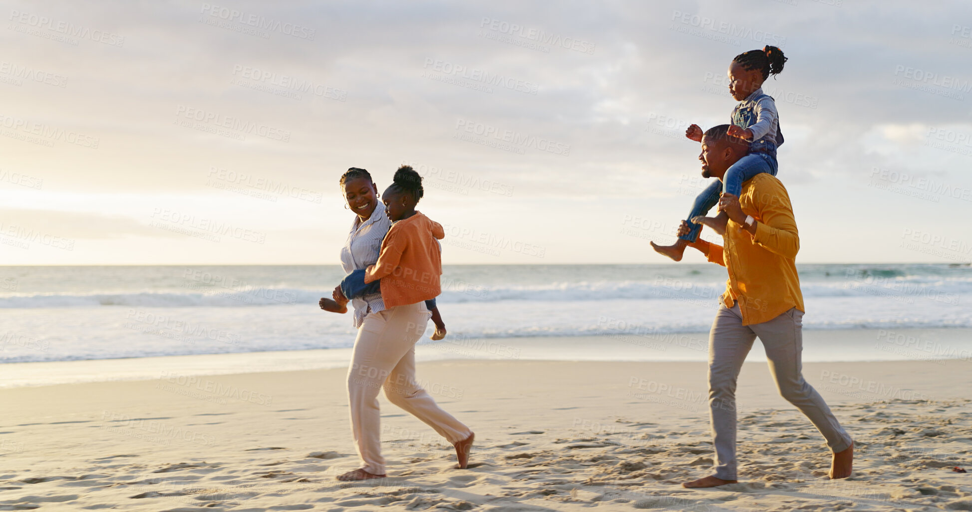 Buy stock photo Sunset, happy and walking black family on the beach for bonding, travel or on holiday together. Smile, nature and an African mother and father carrying children while on a walk by the sea on vacation