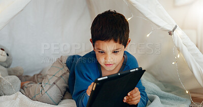 Tablet, relax and boy child in a tent playing an online game on the internet in the living room. Happy, entertainment and kid watching a movie, video or show on a digital technology in a blanket fort