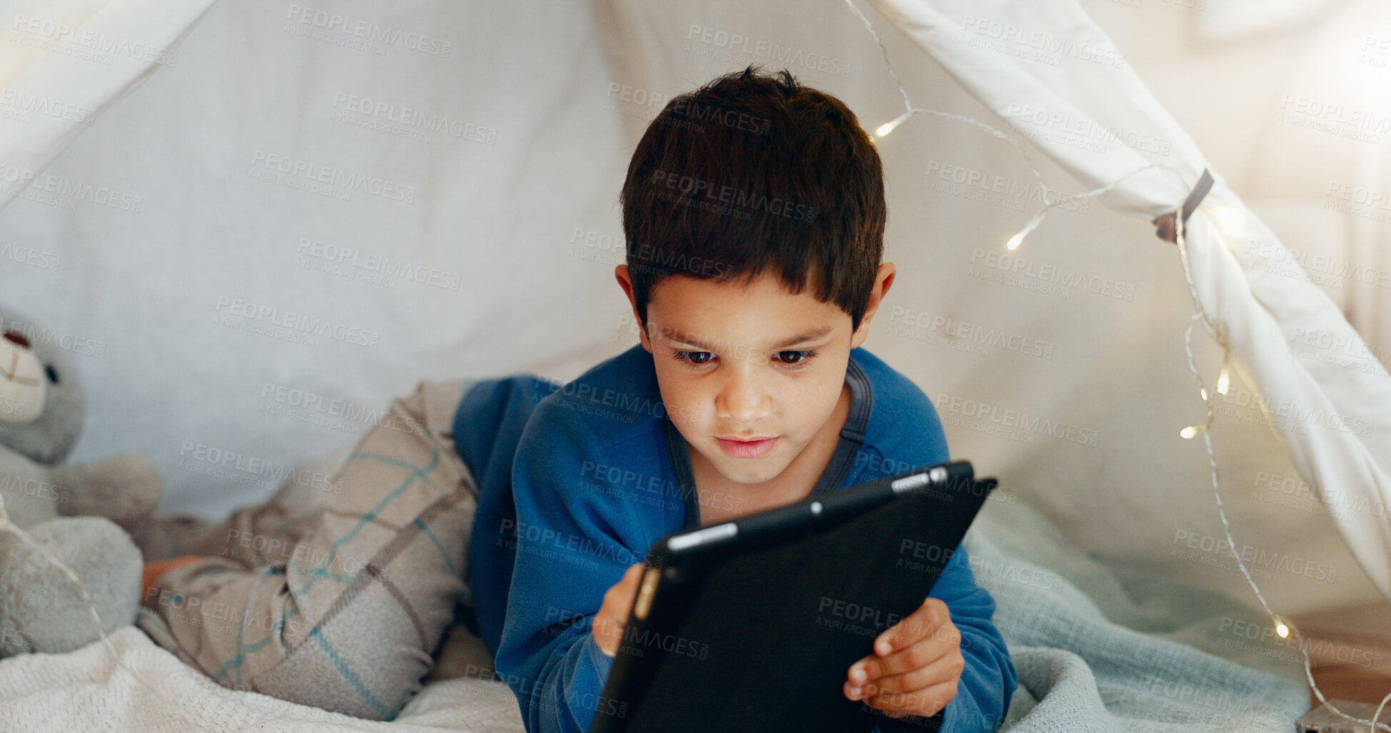 Buy stock photo Tablet, relax and boy child in a tent playing an online game on the internet in the living room. Happy, entertainment and kid watching a movie, video or show on a digital technology in a blanket fort