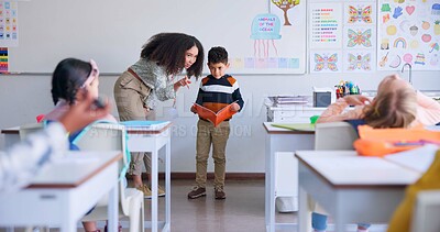 Teacher, child and reading a book in class for learning, development and communication. A boy kid or student and woman teaching language, support and assessment in elementary classroom at school