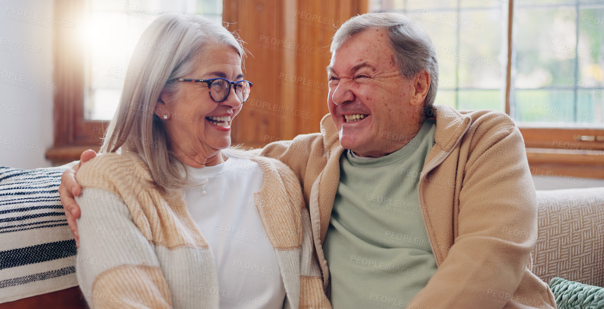 Buy stock photo Senior couple, happiness and retired while laughing, talking and smile, couch and touch. Retirement, old age home and elderly in living room, couch and bonding together for quality time, hug or care