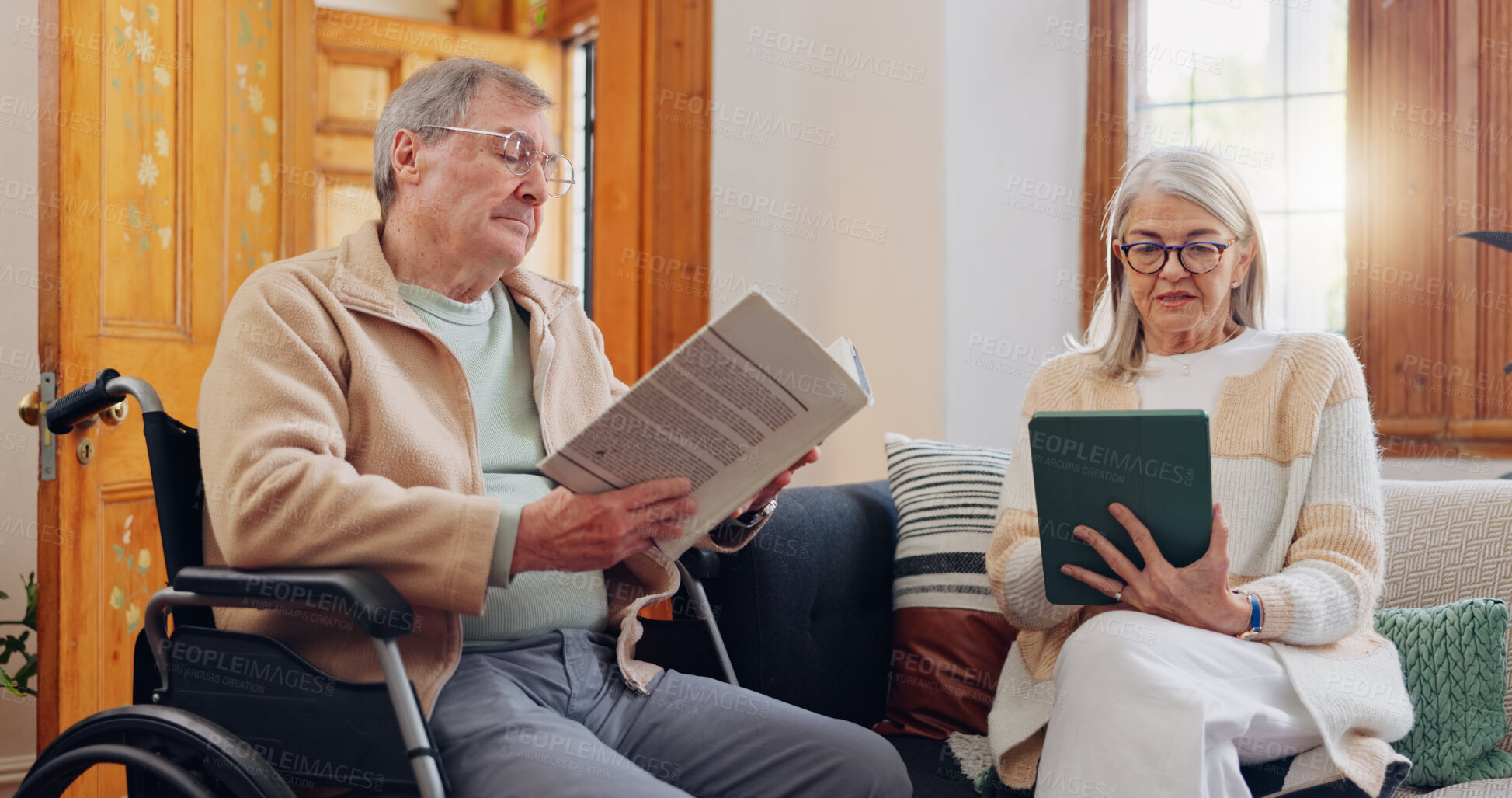 Buy stock photo Elderly couple and care, retirement house and wheelchair in nursing home with people reading books, news or tablet with hobbies. Retirement and relax in house living room with notebook