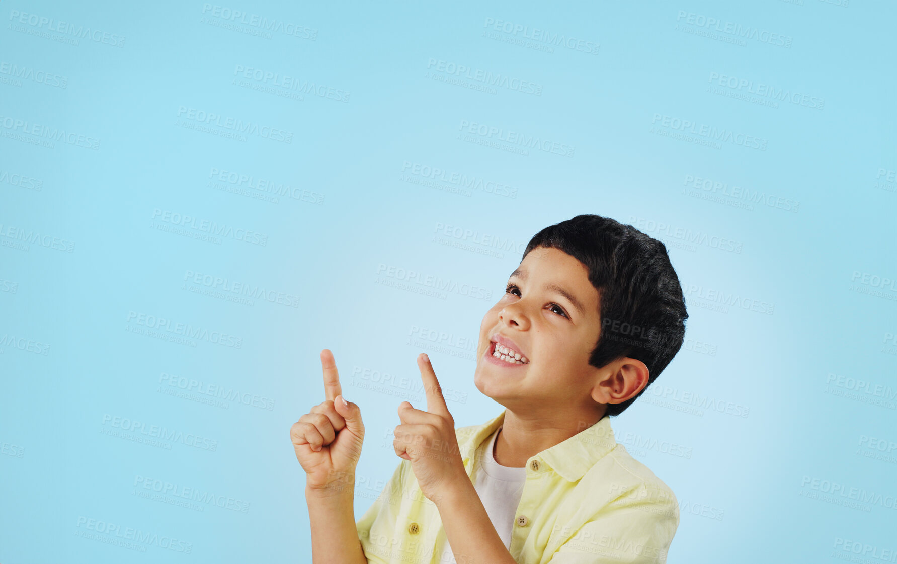 Buy stock photo Kid, boy and smile while pointing in studio on blue background with mockup for announcement, offer or deal. Youth, happy and excited about notification on social media, online or digital marketing