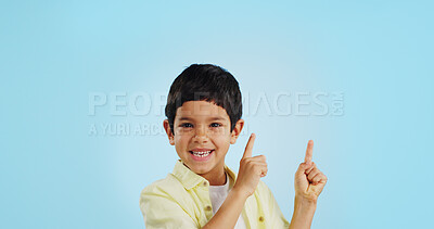 Buy stock photo Kid, boy and smile while pointing in studio on blue background with mockup for announcement, offer or deal. Youth, happy and excited about notification on social media, online or digital marketing