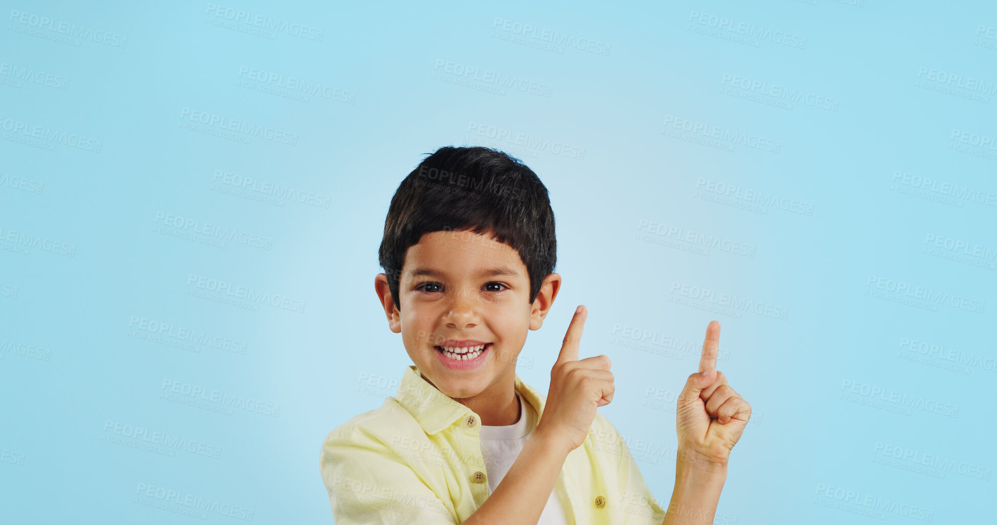 Buy stock photo Kid, boy and smile while pointing in studio on blue background with mockup for announcement, offer or deal. Youth, happy and excited about notification on social media, online or digital marketing