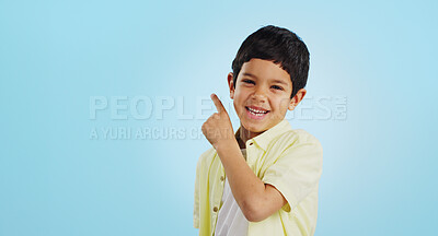 Boy, smile and pointing with excitement in studio on blue background in mockup for opportunity, deal or alert. Youth, kid and happy with offer, discount or announcement on social media for consumers
