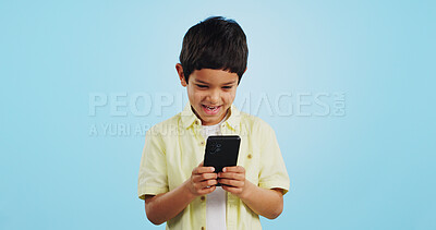 Buy stock photo Kid, phone or typing to chat in studio on social media to play mobile games or download app. Blue background, scroll or boy child reading notification for online communication or watch fun multimedia