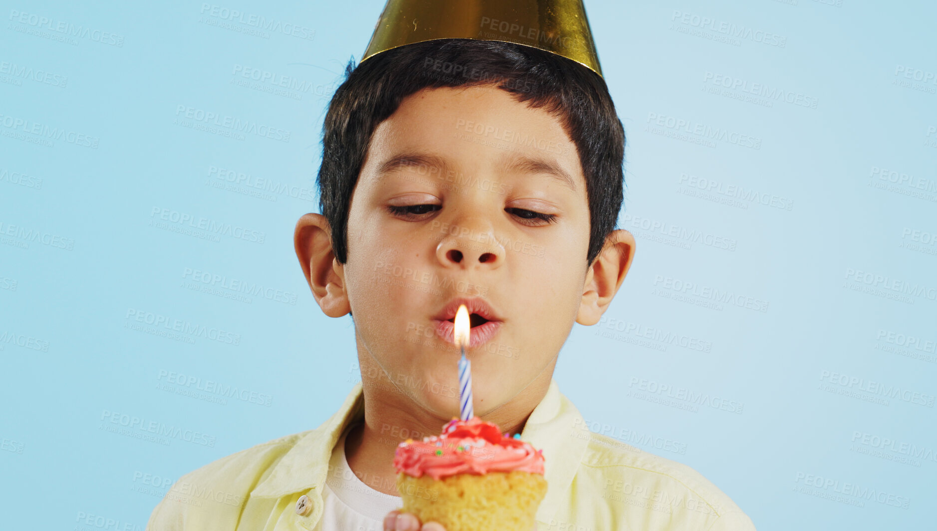 Buy stock photo Blowing candle, child and a cupcake for a birthday, celebration or a wish on a studio background. Happy, face portrait and a hungry boy kid with party food, cake or dessert for a present or event