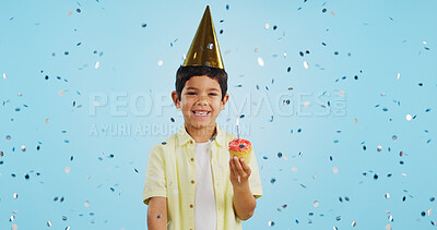 Happy birthday, child and portrait with confetti in party with cupcake, hat and happiness in studio blue background. Congratulations, kid and boy with cake, glitter and smile on face for magic event