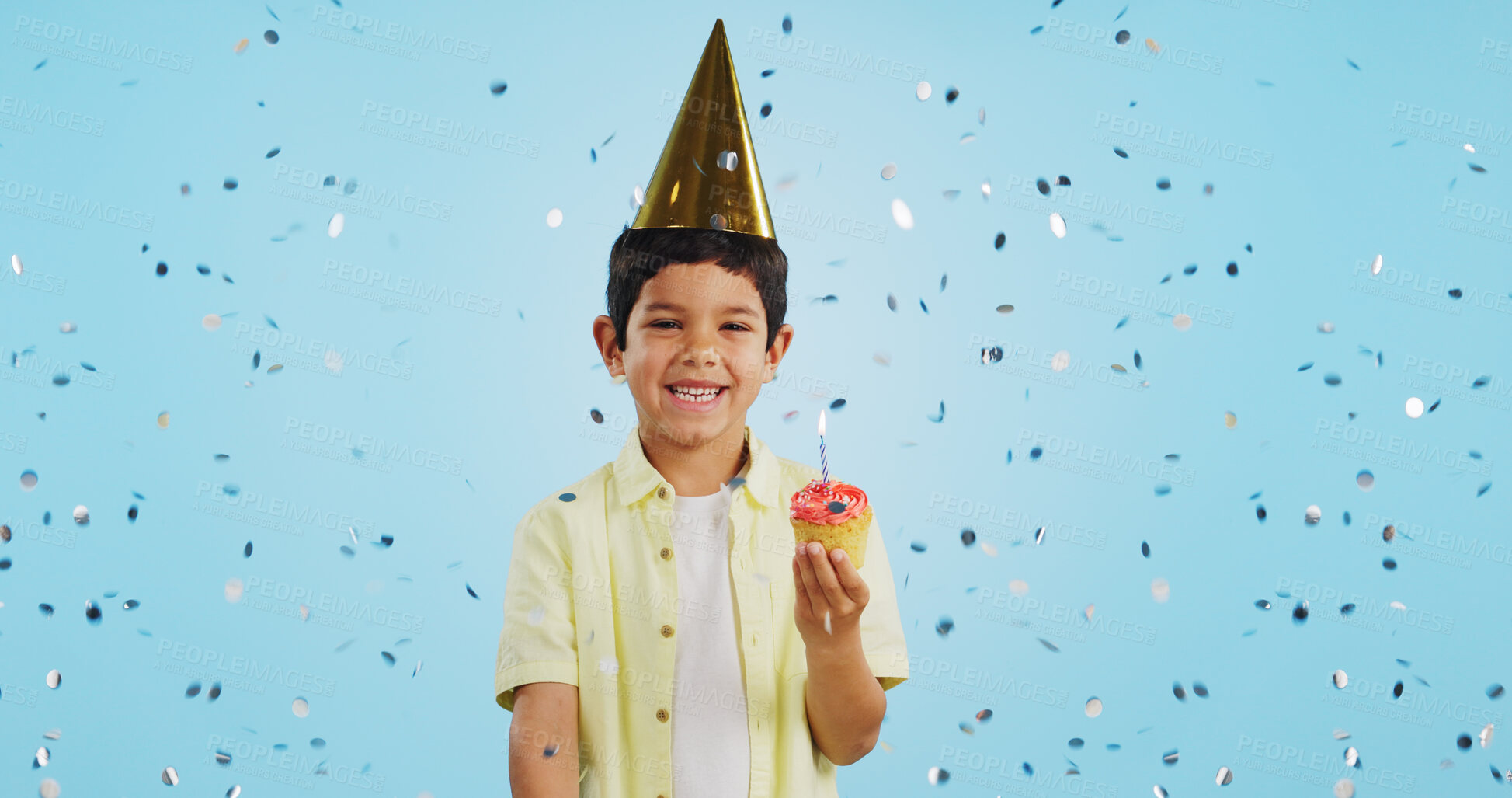 Buy stock photo Happy birthday, child and portrait with confetti in party with cupcake, hat and happiness in studio blue background. Congratulations, kid and boy with cake, glitter and smile on face for magic event