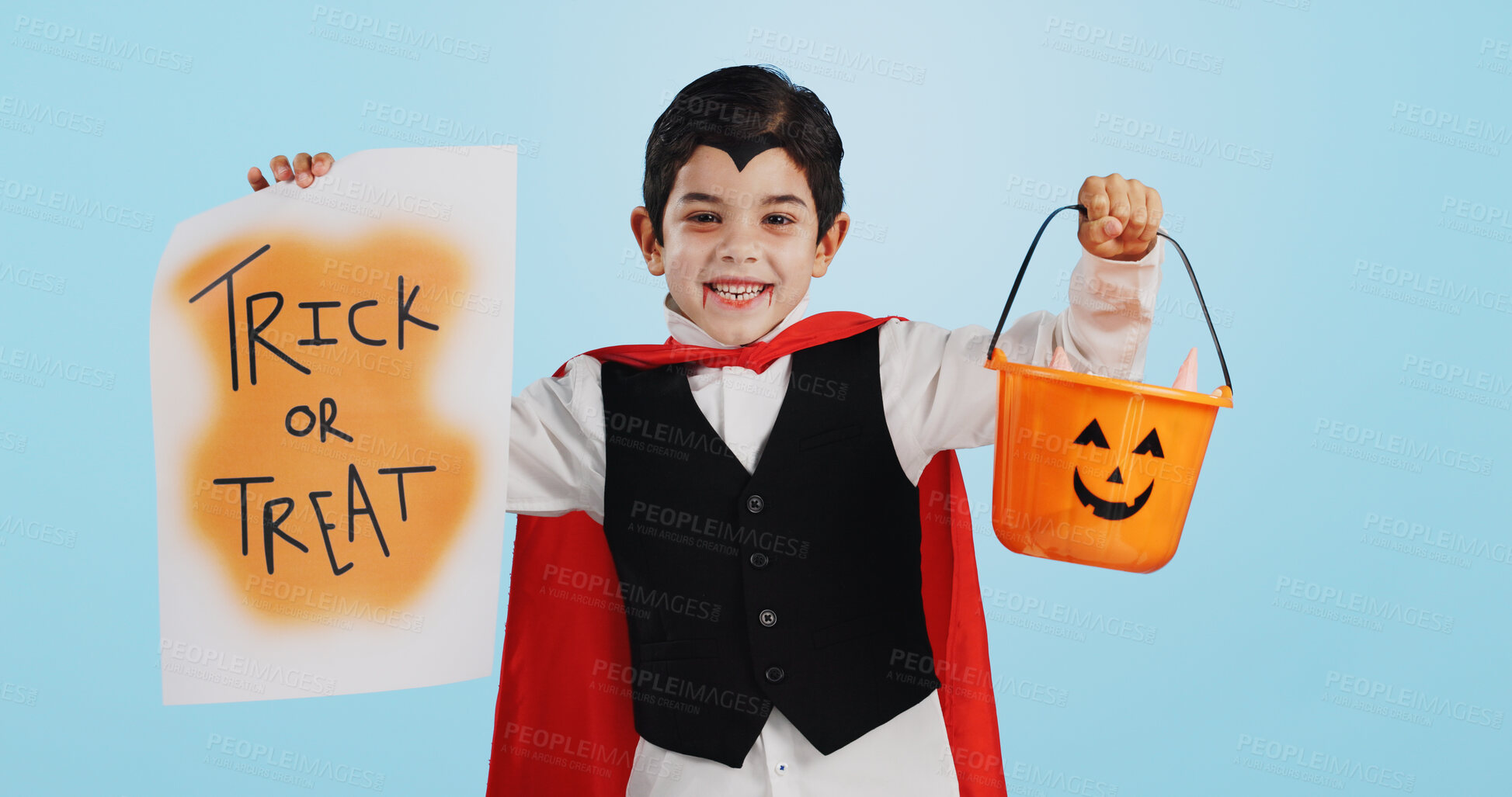 Buy stock photo Halloween, poster and portrait of child with basket of sweets for candy isolated in studio blue background and happy. Holiday, laughing and kid in vampire costume for celebration in fantasy festival