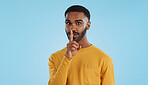 Secret, face and man with finger on lips in studio for quiet, privacy or hush news on blue background. Whisper, drama and portrait of guy model with confidential hand emoji for gossip or announcement