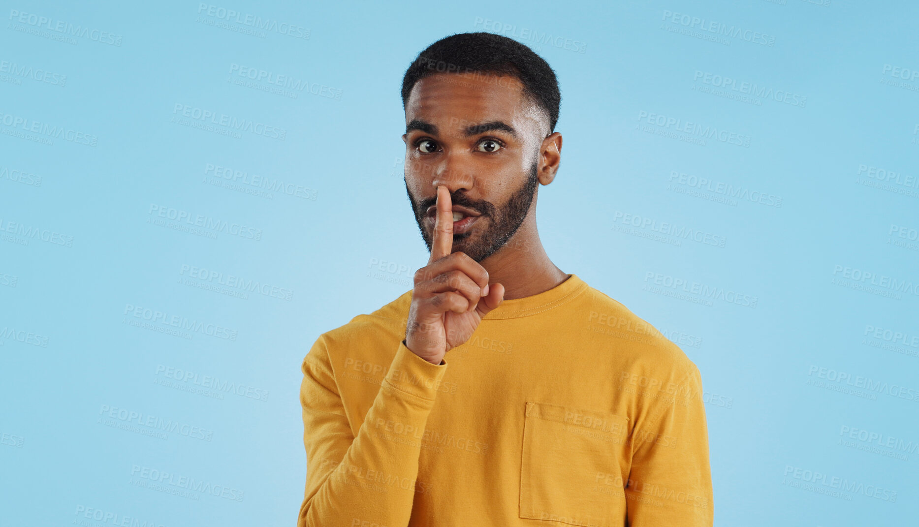 Buy stock photo Secret, face and man with finger on lips in studio for quiet, privacy or hush news on blue background. Whisper, drama and portrait of guy model with confidential hand emoji for gossip or announcement