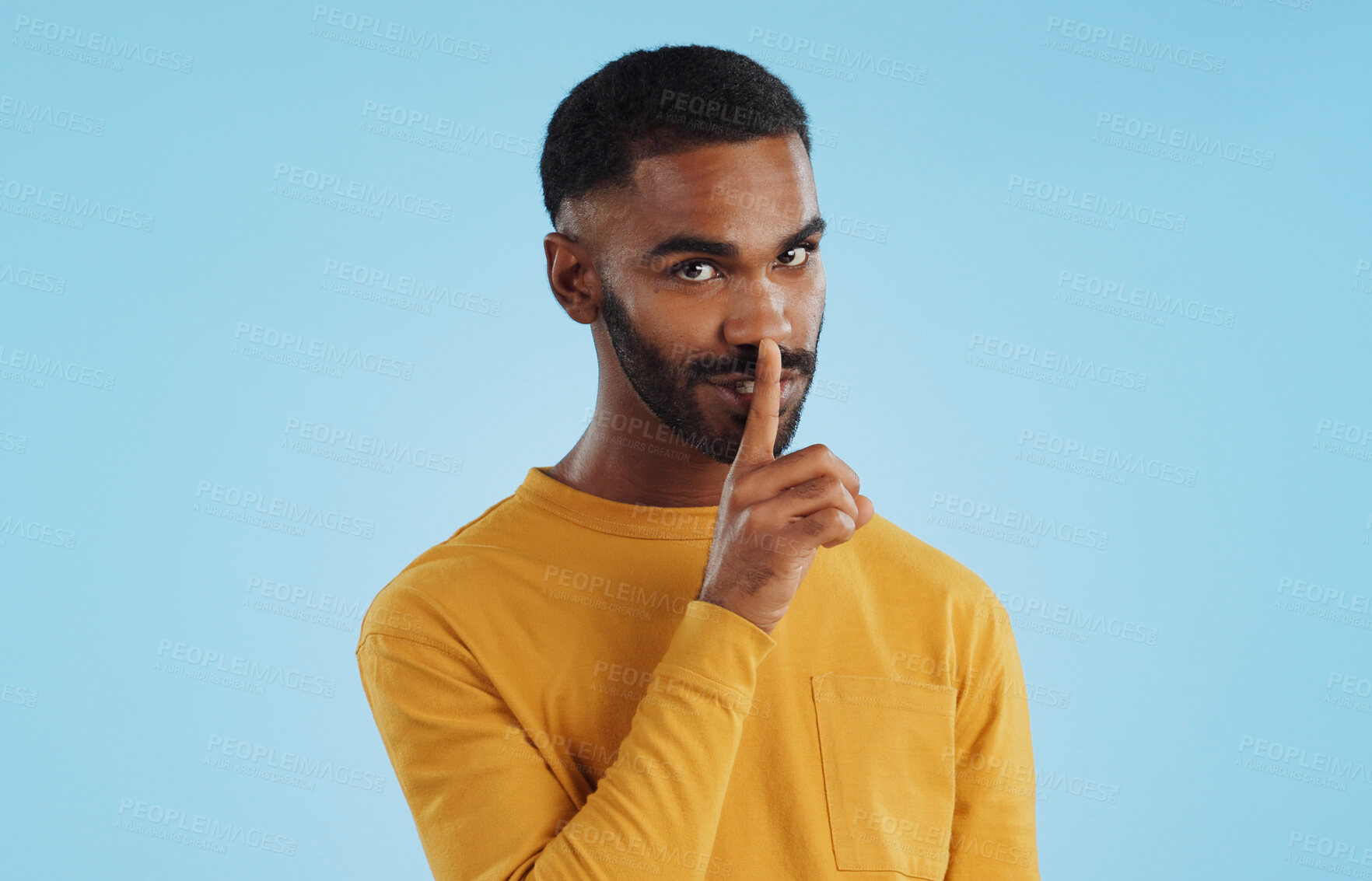 Buy stock photo Secret, face and man with finger on lips in studio for quiet, privacy or hush news on blue background. Whisper, drama and portrait of guy model with confidential hand emoji for gossip or announcement