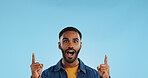 Happy man, pointing and news announcement with portrait in studio, surprise emoji and advertising. Mockup, mexican person and smiling in casual fashion for offer and notification by blue background