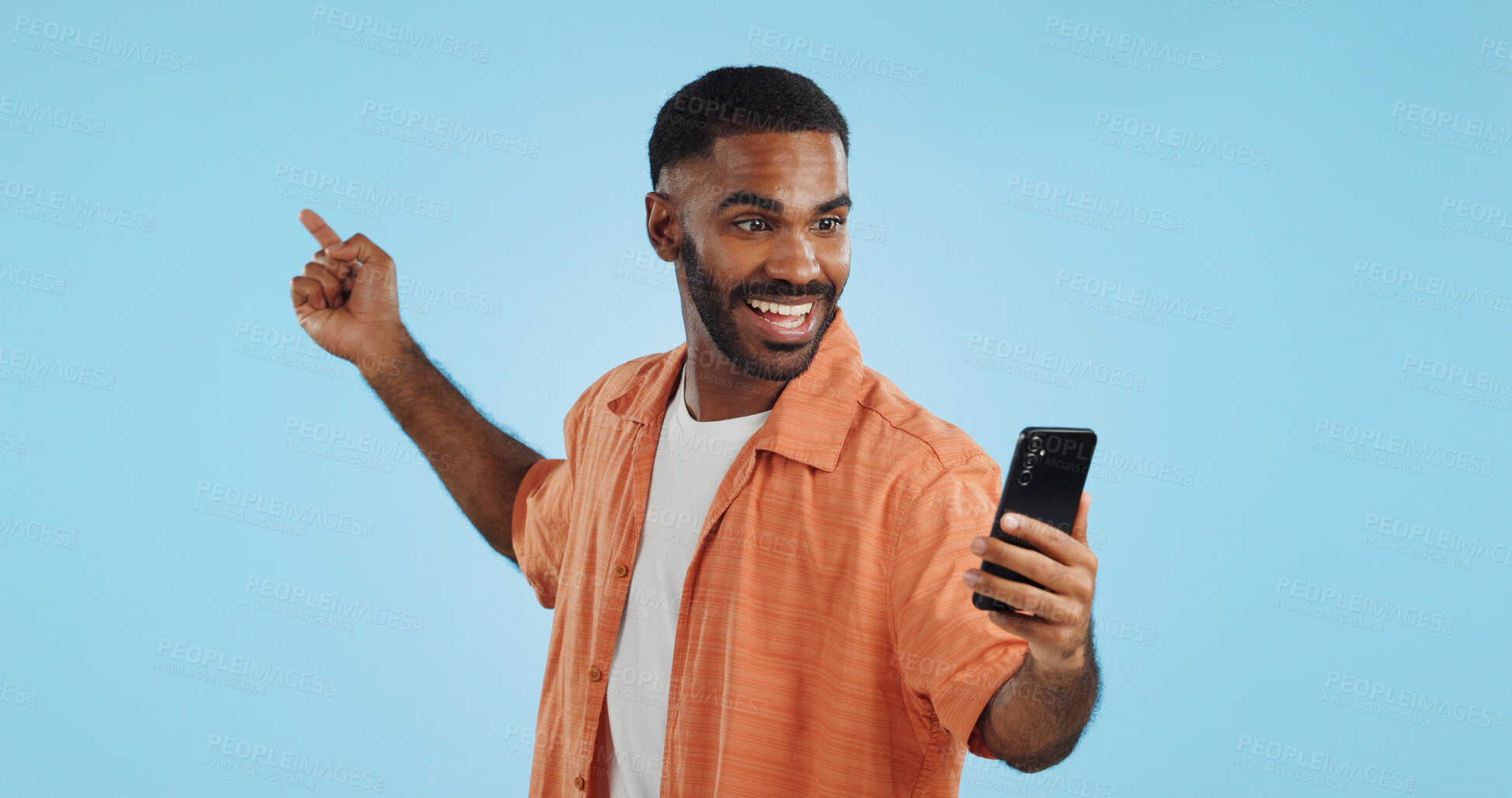 Buy stock photo Happy, face and man with phone in hand pointing in studio for news, smartphone presentation or platform offer on blue background. Smile, portrait and male model show promo, launch or space for coming soon announcement