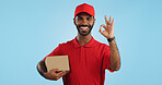 Delivery man, box and okay hands for success, product excellence and courier services in studio. Happy face of supply chain worker or african person for package or distribution on blue background