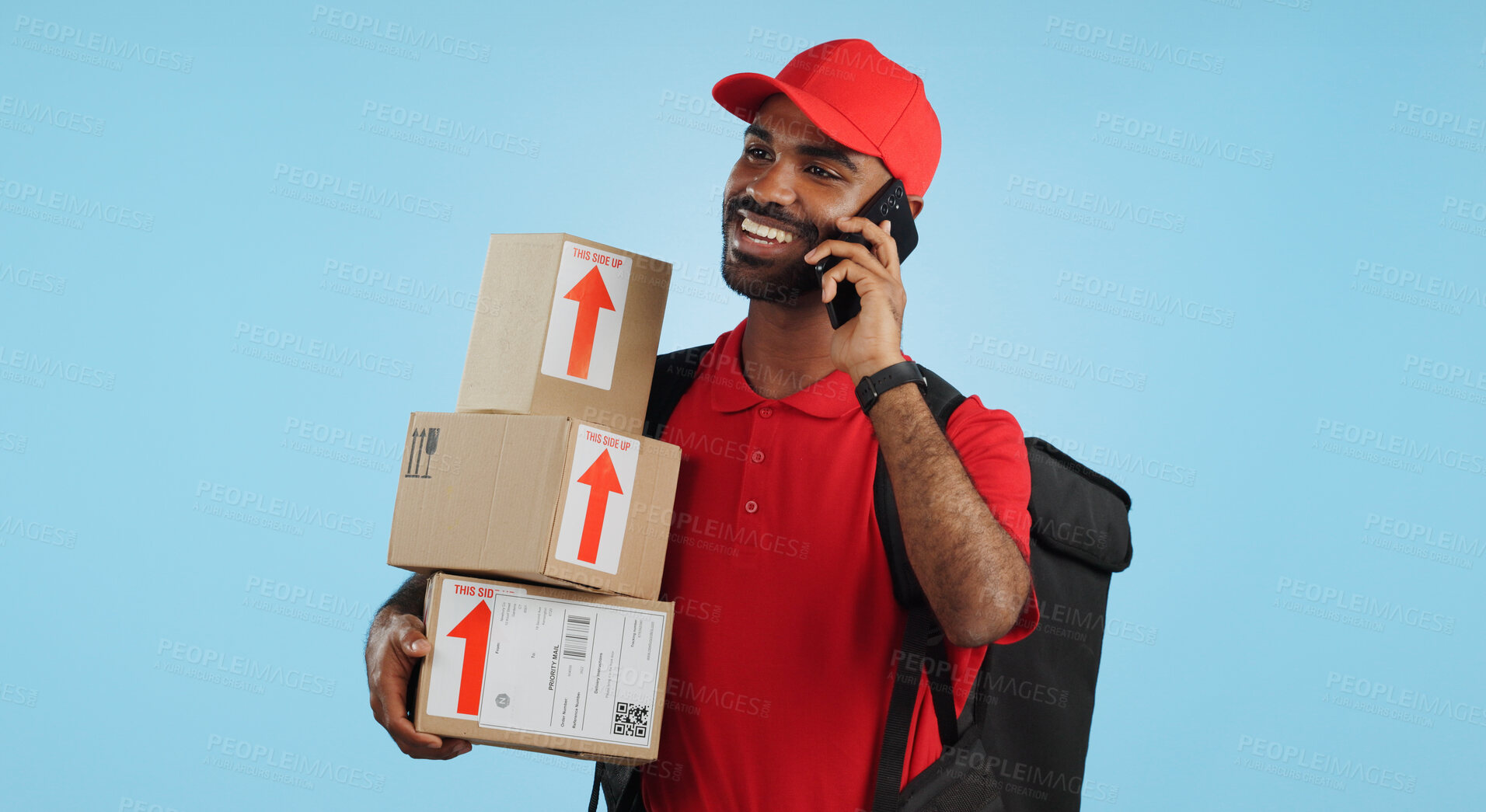 Buy stock photo Man, logistics and courier with cellphone in communication to client, delivery or boxes in studio. Indian person, supply chain and cargo in conversation with customer, packages and blue background