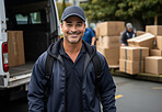 Happy uniformed delivery man or courier in city street. Boxes being loaded in background.