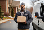 Portrait of happy uniformed delivery man in city street. Package in hand.