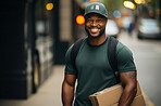 Portrait of happy uniformed delivery man in city street. Package in hand.