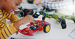 Robotics, boy and technology in classroom for education or learning electronics with car toys for innovation. School kids, learners and transportation knowledge in science class for research or study