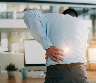 Buy stock photo Rearview shot of a young businessman holding his back while standing at his desk