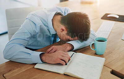 Buy stock photo High angle shot of a young, overworked businessman sleeping at his desk
