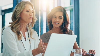 Buy stock photo Shot of two businesswomen having a discussion while using a laptop