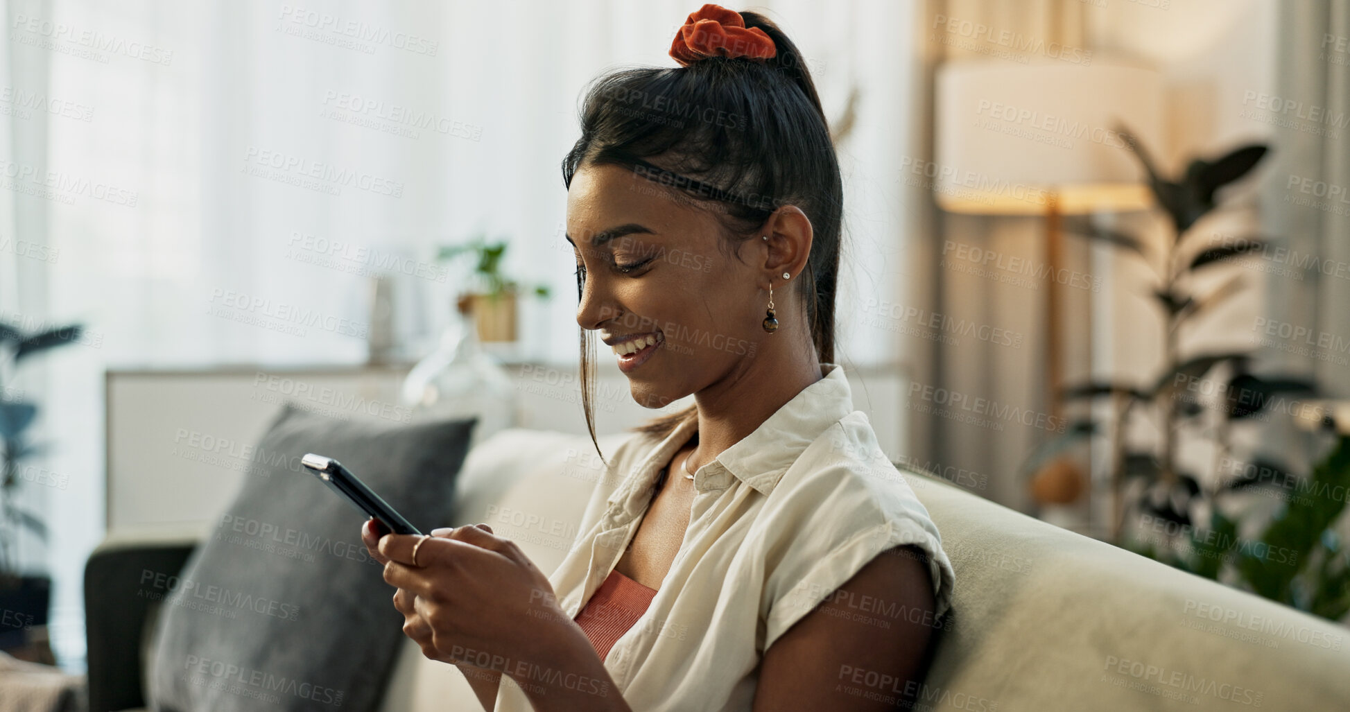 Buy stock photo Woman, typing and smile in home with smartphone, social network or update multimedia subscription on sofa. Happy indian girl relax with cellphone app, download mobile games or chat to digital contact