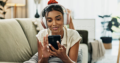 Phone, music headphones and happy woman on sofa in home, listening to audio or video app to relax. Smartphone, sound and Indian person on radio or typing on social media in living room on mobile tech