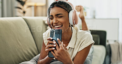 Buy stock photo Woman, singing and phone with headphones on sofa, smile or relax for comic performance in living room. Girl, smartphone and audio streaming subscription with voice, noise or karaoke on couch in house