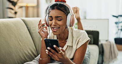 Phone, music and happy woman singing on sofa in home, dance and listening to audio. Smartphone, excited Indian person on headphones for radio, sound or freedom in living room on mobile app technology