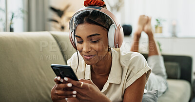 Phone, music headphones and happy woman on sofa in home, listen to audio and video app to relax. Smartphone, sound and Indian person on radio or typing on social media in living room on mobile tech