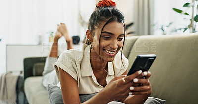 Phone, smile and woman on sofa typing in home, social media and reading email notification to relax. Smartphone, happy and Indian person in living room on mobile app, scroll website and communication