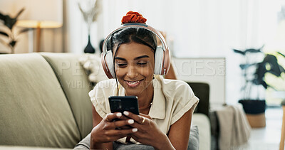 Smartphone, music headphones and happy woman on sofa in home, listening to audio or video app to relax. Phone, sound and Indian person on radio or typing on social media in living room on mobile tech