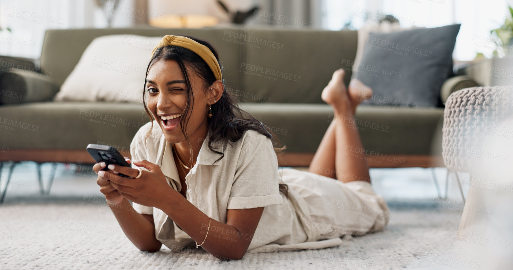 Buy stock photo Woman, phone and portrait with wink, relax and lying on floor for flirting, secret and typing in living room of home. Indian, girl and smartphone on ground for chat, texting or technology with emoji