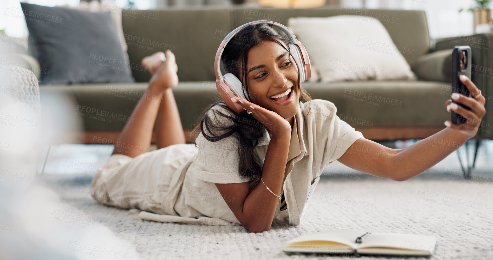 Buy stock photo Woman, selfie and lying on floor with headphones or smile for social media, profile picture or internet post in living room of home. Indian, girl and smartphone on ground or happiness and joy on tech