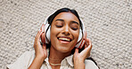 Headphones, happy and young woman in the living room laying on the mat listening to music. Smile, calm and Indian female person streaming podcast, radio or playlist and chilling on the floor at home.